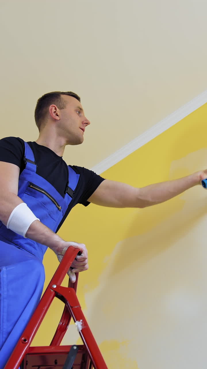 Apartment redecoration and home construction. Caucasian man paints the wall with roller. Vertical video