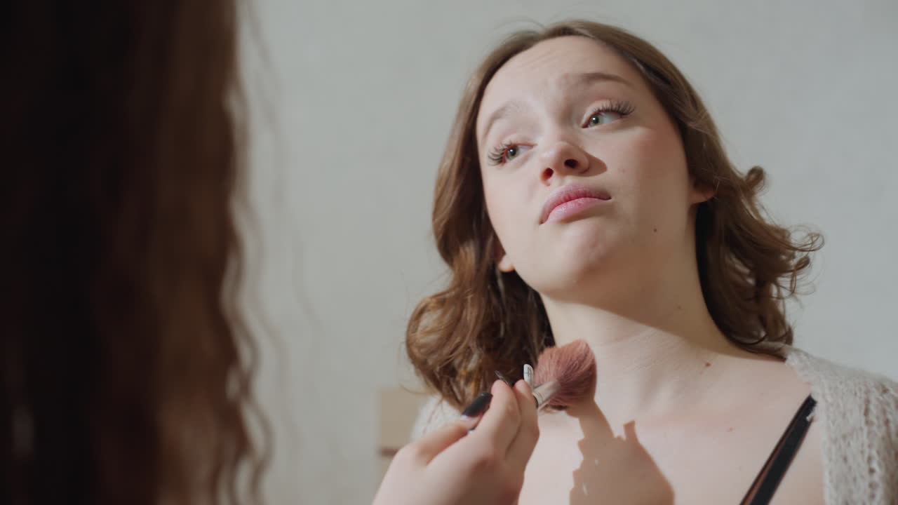 White Woman Receiving Makeup Application Collarbone, Close Intimate Scene As Friend Brushes Bronzer Across DColletage, Soft Natural Light, Cozy Bedroom, Candid Smile And Playful Conversation