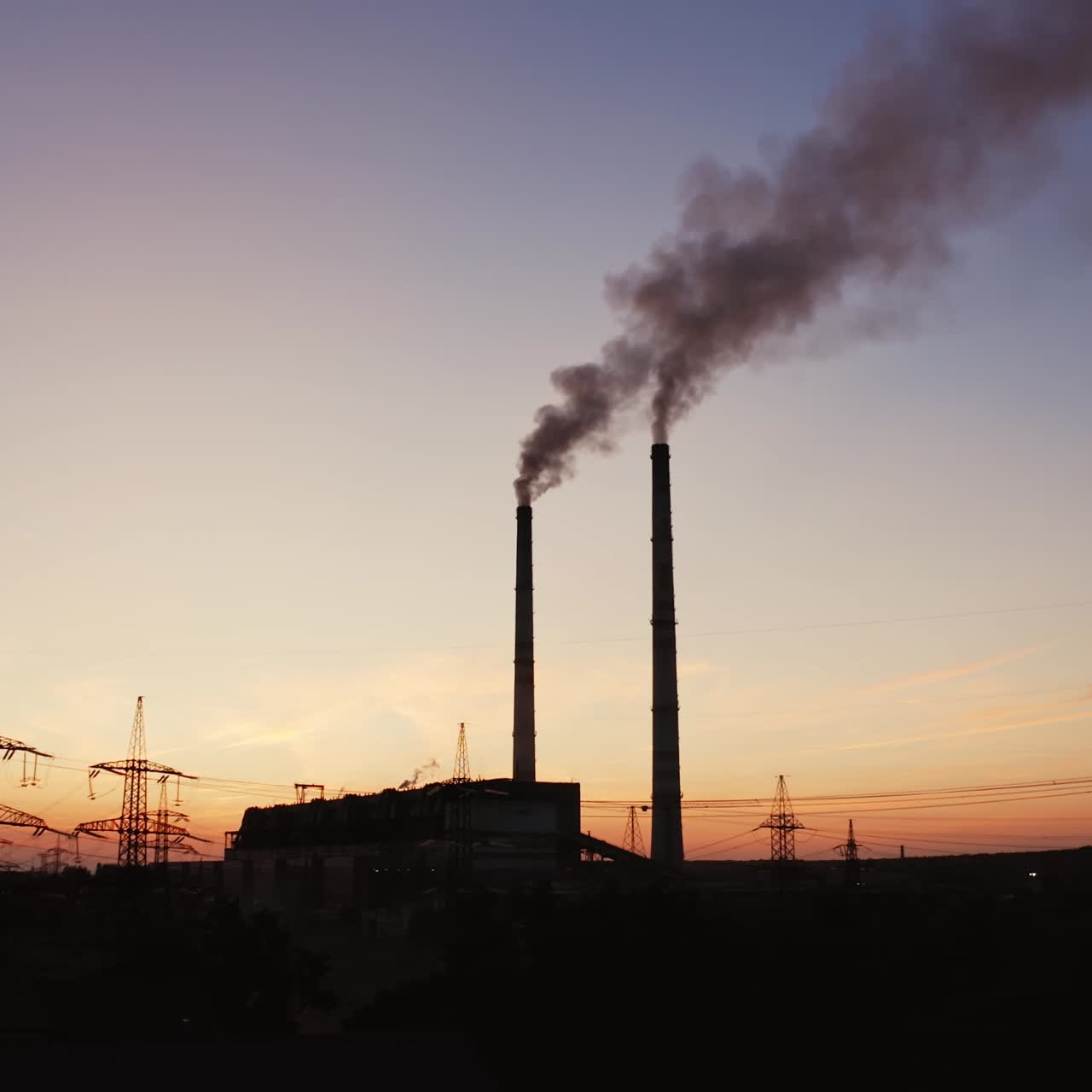 Factory tubes on the sunset background. Smoke from the pipes. Pollution concept. Video from the air.
