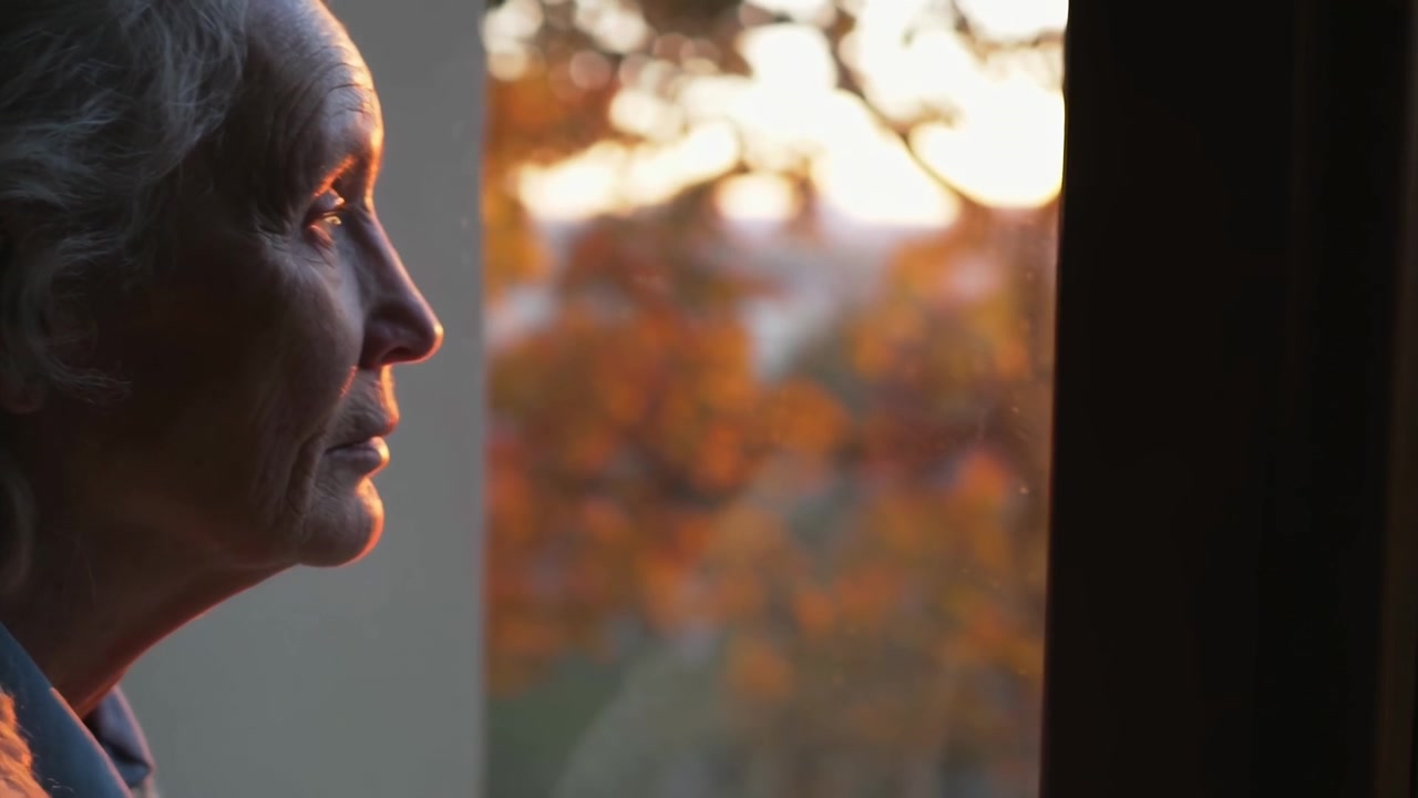 Senior Woman Looking Out of Window at Sunset