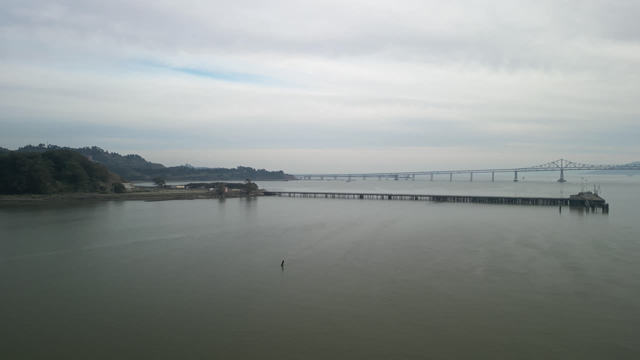 Coastal aerial drone shot of Point Molate Beach, showcasing the tranquil bay and nearby Richmond–San Rafael Bridge.