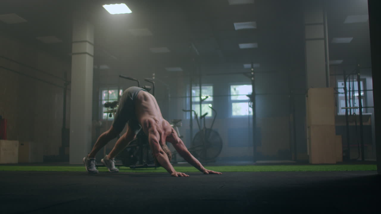 Man doing push ups in a gym. Exhaling and inhaling after push-ups and exercise. Perfect for fitness and workout. Young sports man performs pushups in the gym. The athlete is engaged in fitnes