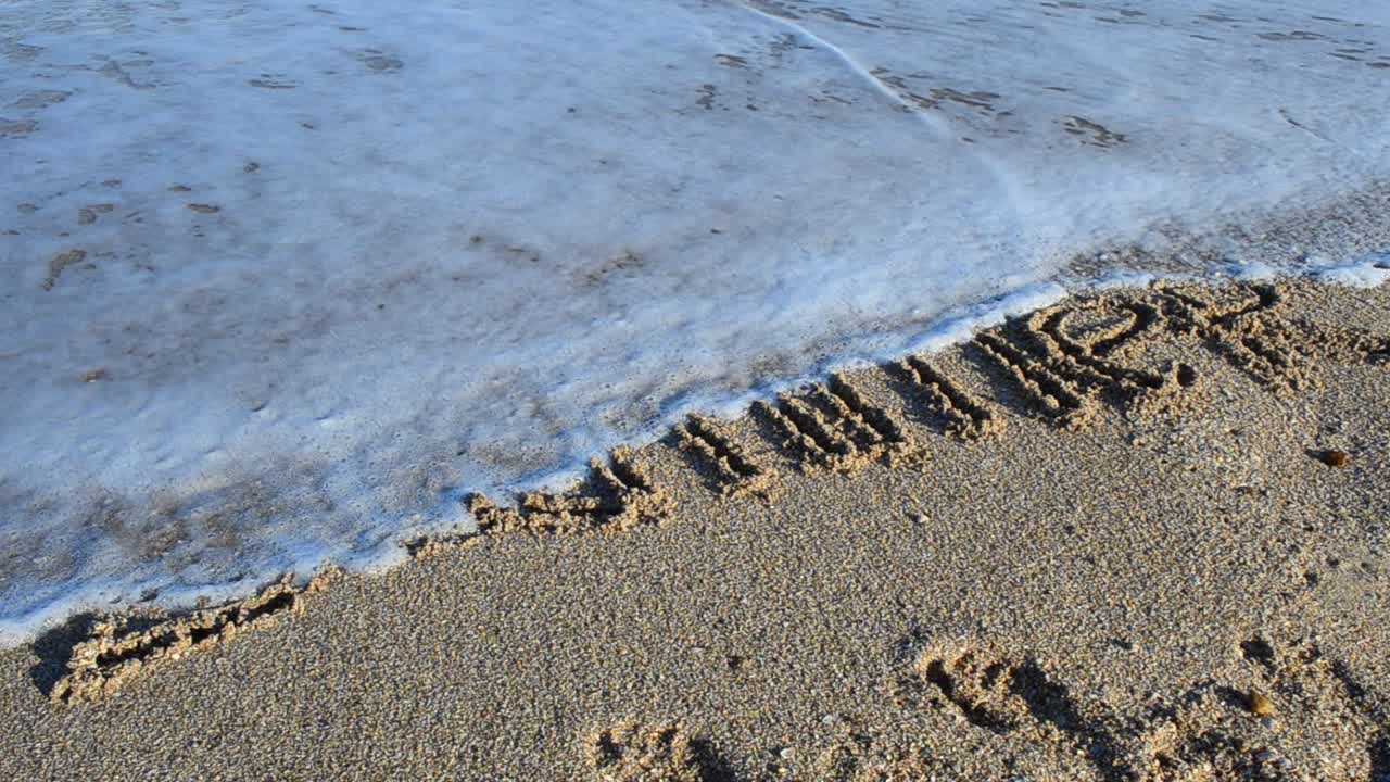Inscription summer on sand. The inscription is washed away by a sea wave. Shooting on the beach