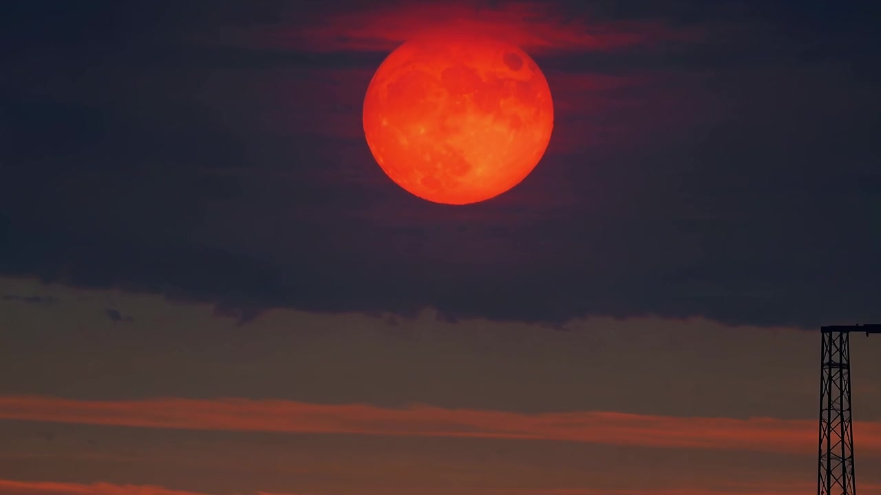 Full Moon Rising Behind Dark Clouds at Sunset