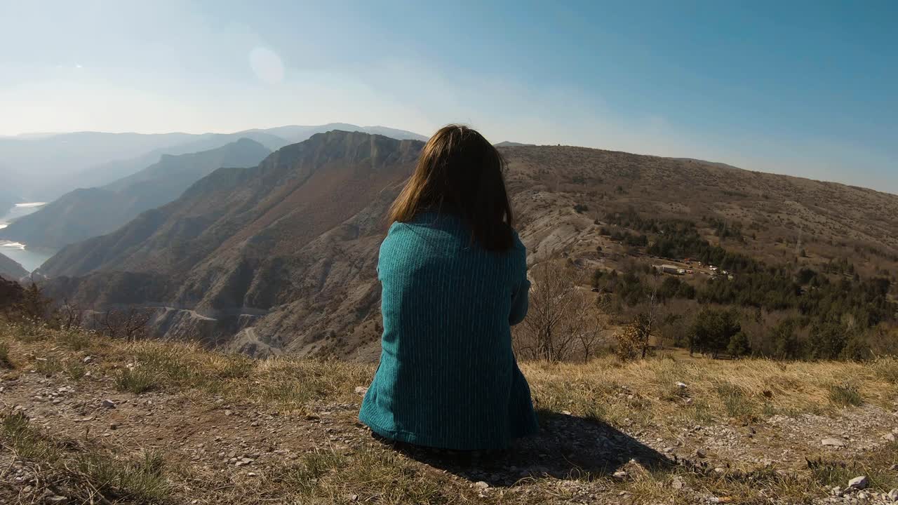 chica sentada en una montaña en un día soleado con un hermoso lago de cañón en el fondo