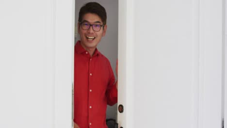행복 한 아시아인 이 앞 문 을 열고 미소 짓고 집 에 방문 한 사람 을 환영 한다