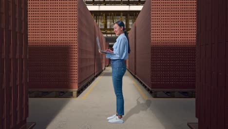 full body side view of asian female with her laptop with red brick packed in stacks are stored, typing on her laptop's keybaord with meditation