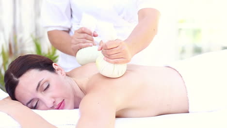 brunette having massage with herbal compresses