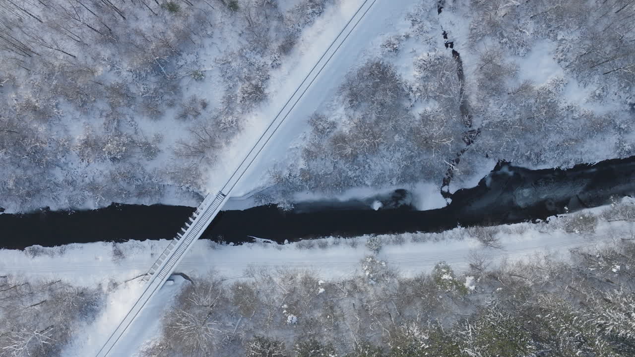 부분적으로 얼어붙은 강을 가로지르는 겨울 다리, 공중에서 위에서 아래로