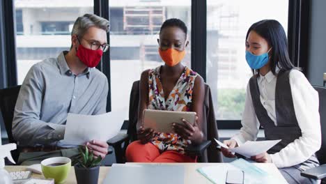 diversos colegas de oficina con máscaras faciales discutiendo juntos en una oficina moderna