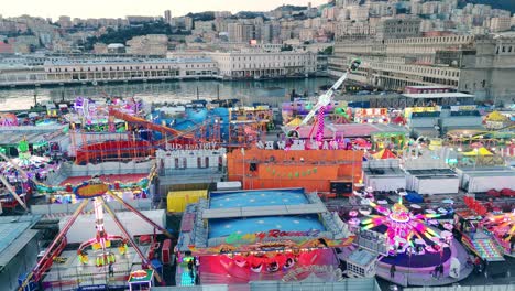 An-italian-lunapark-lit-up-at-blue-hour,-vibrant-and-bustling,-aerial-view