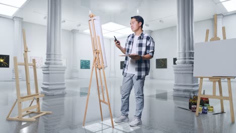 cuerpo lleno de artista masculino asiático que encuentra inspiración en el teléfono inteligente mientras pinta en lienzo con pinturas al óleo y pincel en la galería