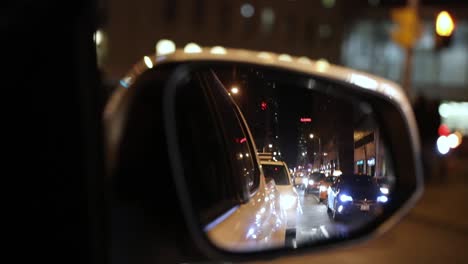 conducción de automóviles a través de la ciudad urbana, mirando a través del espejo retrovisor