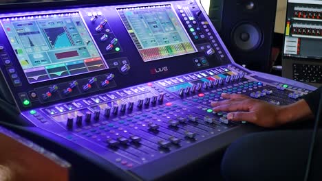 a medium shot capturing a hand operating an audio mixer, skillfully adjusting knobs and sliders