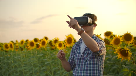 a man works with augmented reality glasses on the field with sunflowers. these are modern technologies.