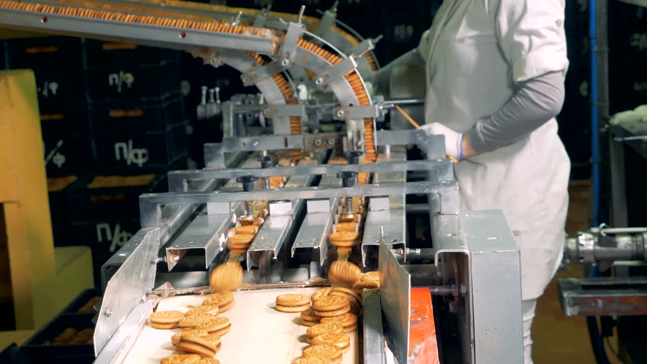 Finished biscuits falling from the conveyor while a person is controlling the process