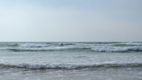 sit down paddle boarder in the water off mawgan porth beach, cornwall, uk