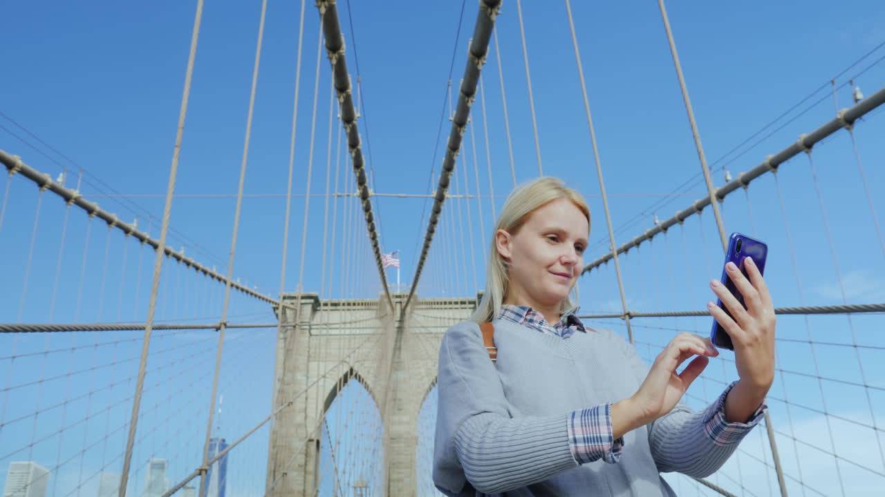 una mujer se toma fotos en el famoso puente de brooklyn, una de las principales atracciones de new