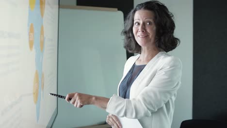 successful businesswomen pointing with pen, talking and smiling