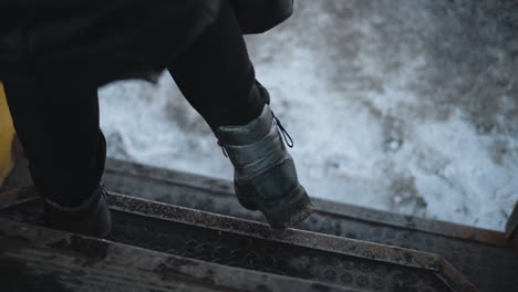 low interior view of locked yellow train door over snowy ground, hinges, door begins opening as passenger steps out at stop, and rubber tread shake with motion during cold winter ride inside