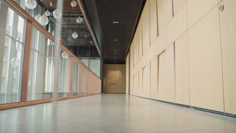 a young businessman with beard in blue suit walks through a hallway carrying a trolley