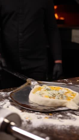 chef preparing a gourmet pizza in a wood-fired oven