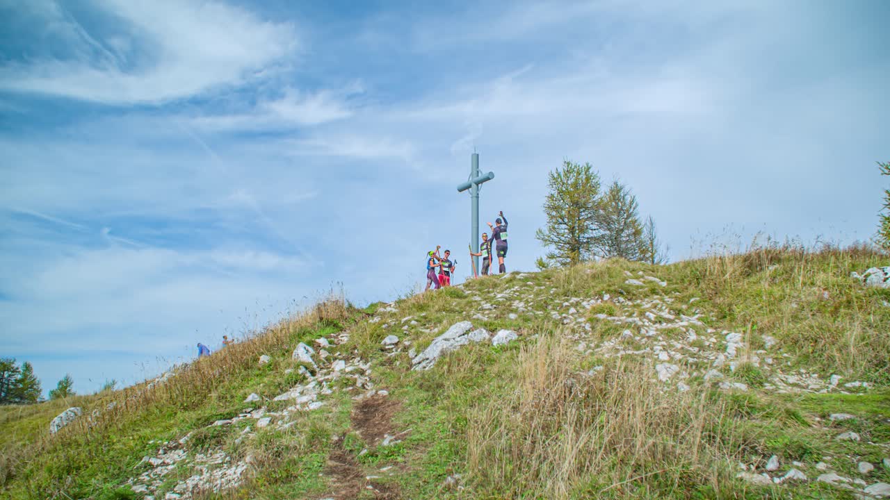 Group Of Trail Runners Reaching Top Of Mountain At Urslja gora in Slovenia And Cheering. Low Angle, Slow Motion