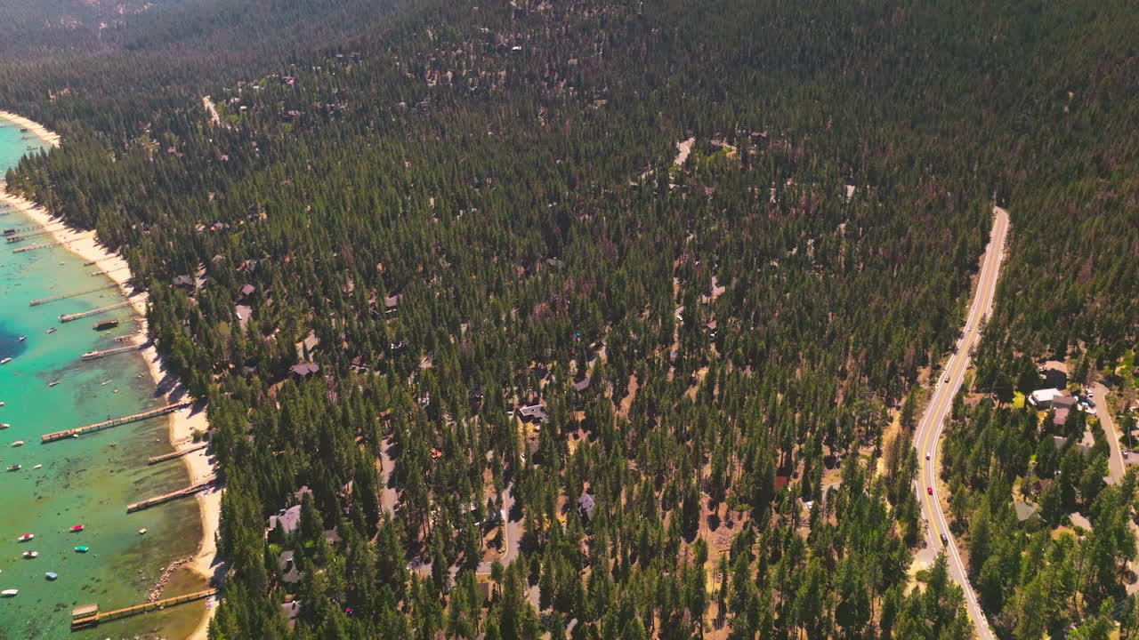Lovely picture of green pine tree forest growing on the mountainous landscape. Many boats on the blue water of lake. Aerial view.