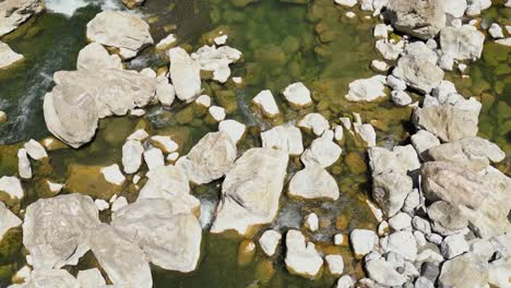 A downward shot reveals the green-colored river with small rocks visible, highlighting the natural details of Tinipak River, Philippines