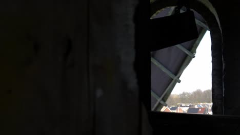 old windmill in operation, view of the blades spinning outside the window against the light