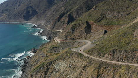 car driving on winding coastal highway with scenic view of pacific ocean, california