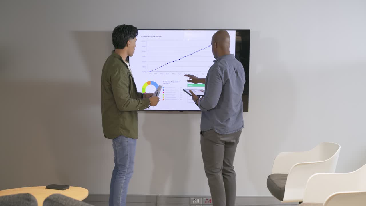 Diverse male coworkers noticing chart trend tapping tablet presenting data planning steps in office