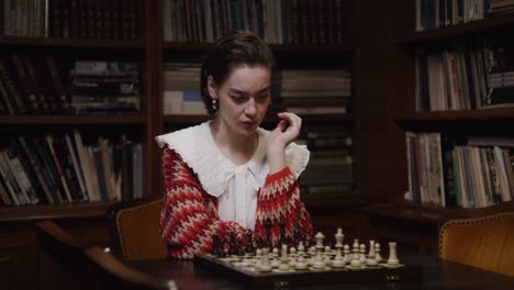 woman concentrating on chess in a vintage library