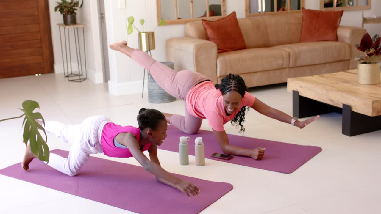 Smartphone starting guided routine, mother-daughter are holding core balance on purple mats at home