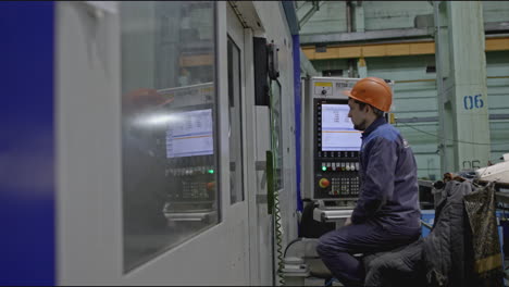 factory worker operating machine control panel