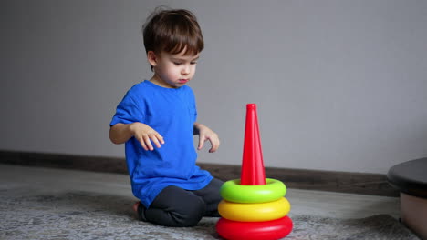 energetic caucasian boy plays with toy pyramid. play time for a toddler at home.