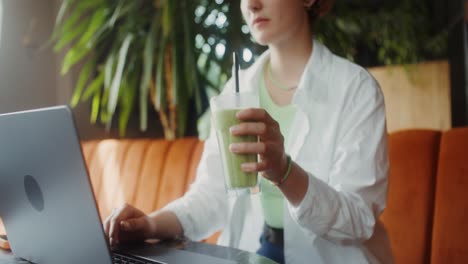 woman working at a cafe with a smoothie