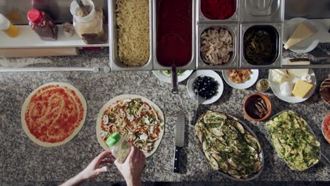 anonymous chef seasoning pizza with aromatic herbs