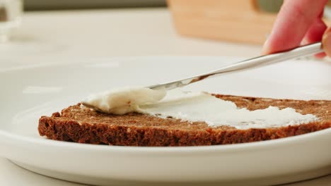 spreading cream cheese on whole grain bread
