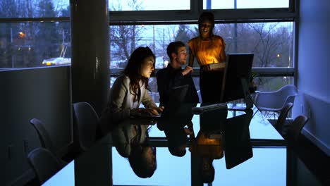 Female-executive-working-over-laptop-while-colleagues-interacting-with-each-other