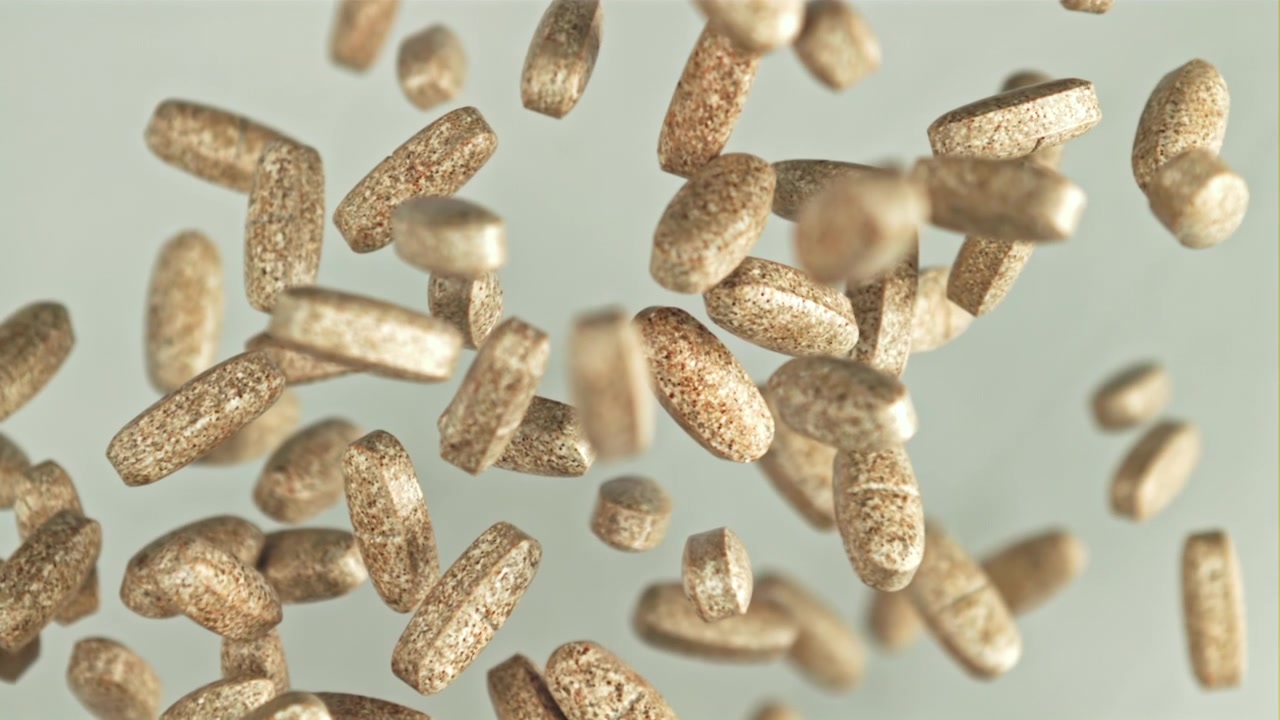 Close-up of Brown Dietary Supplement Pills Falling in Slow Motion