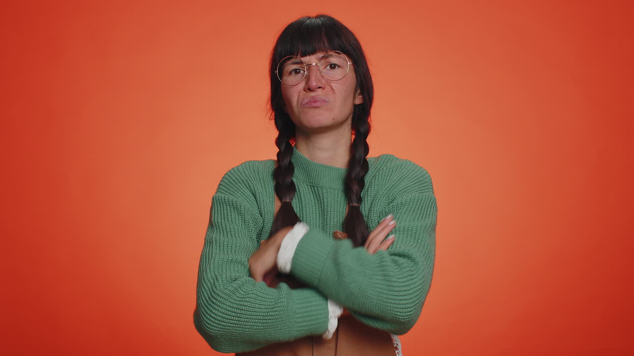 Upset woman in green sweater showing thumbs down sign gesture, disapproval, dissatisfied dislike