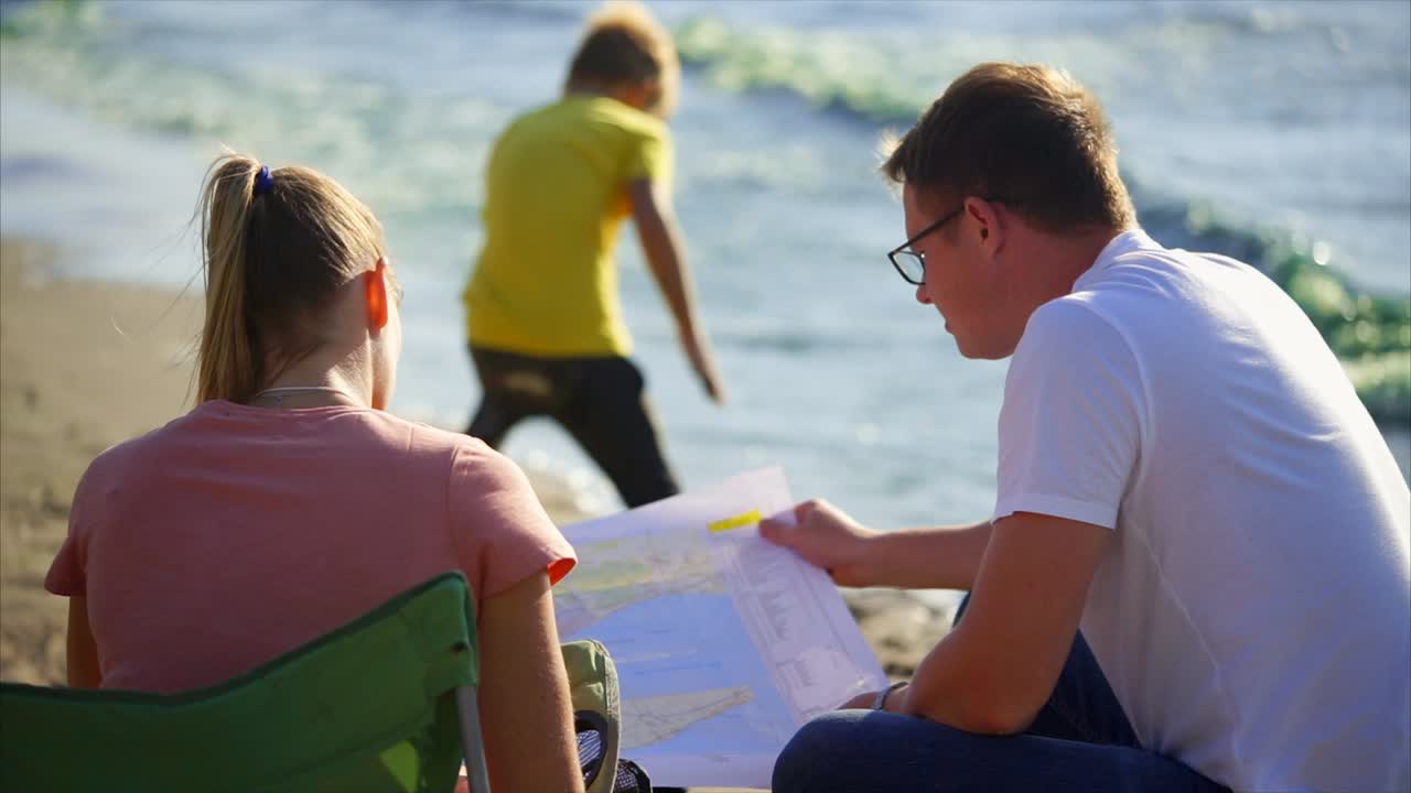 Couple looking at map on the beach