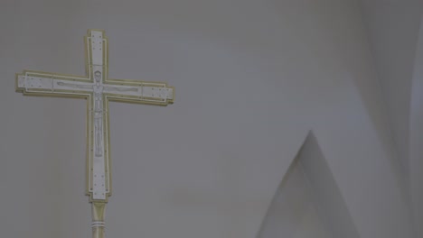 camera pans to a white and gold cross with a crucifix painted on it in a church
