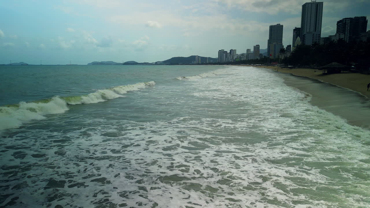 Olas del océano rompiendo en una playa urbana con horizonte de la ciudad