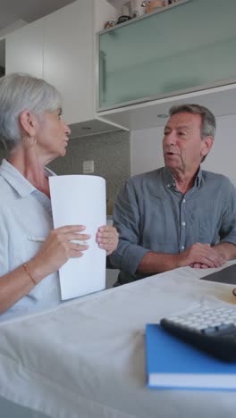Senior couple discussing paperwork in the kitchen