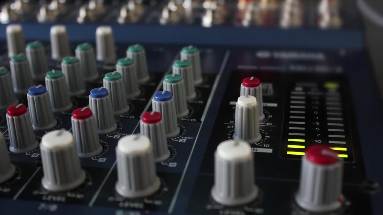 Hand Adjusting Knobs on a Professional Audio Mixer