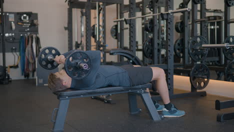 Langhantel-French-Press-Training---Mann-Hebt-Langhantel,-Während-Er-Im-Fitnessstudio-Auf-Einer-Bank-Liegt