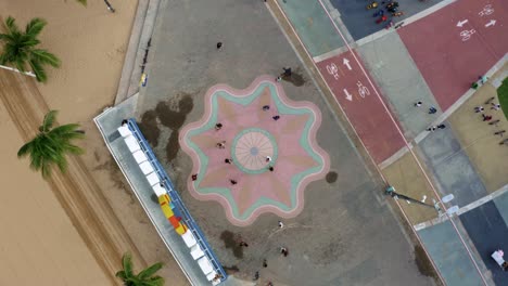 Rotating-Bird's-eye-top-view-of-the-center-plaza-at-the-touristic-Tambaú-beach-boardwalk-in-the-tropical-beach-city-of-Joao-Pessoa,-Paraiba,-Brazil-with-people-gathering-for-pictures-at-the-sign