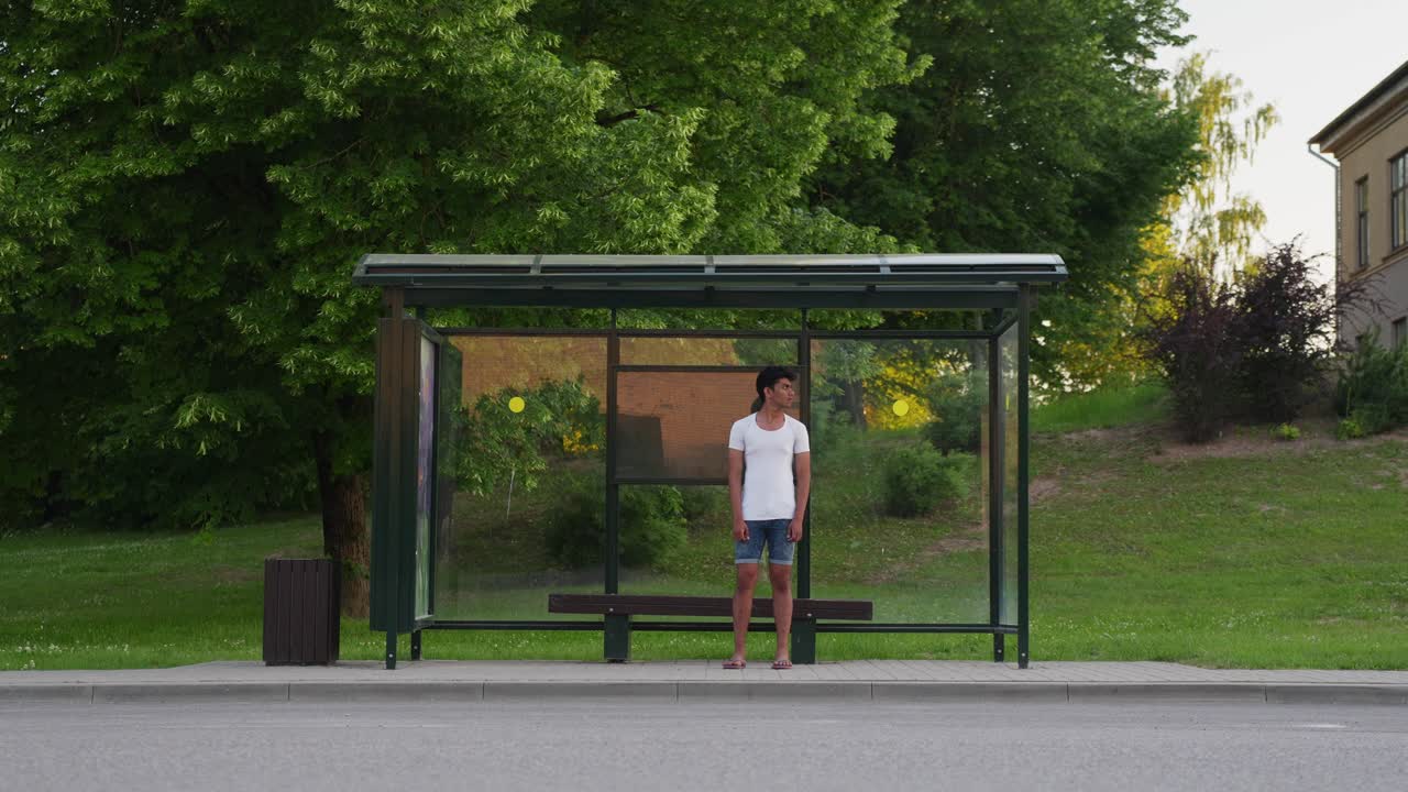 Handsome Srilankan man waiting for bus in public bus stop, handheld view